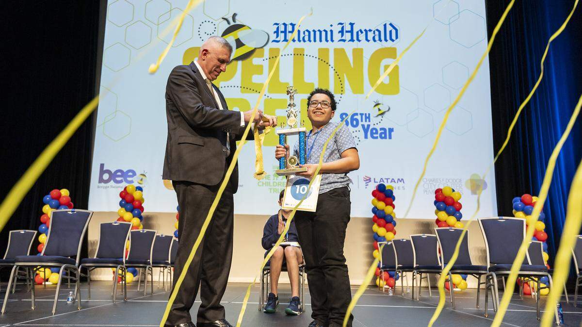 Bob McFarlin, executive vice president of McClatchy, hands Logan Cox, an eighth grader from Herbert A. Ammons Middle School, the first place trophy and a medal after he won the 86th Miami Herald Spelling Bee for Miami-Dade and Monroe County at the Charles F. Dodge City Center on Wednesday, Feb. 25, 2026, in Pembroke Pines, Fla.