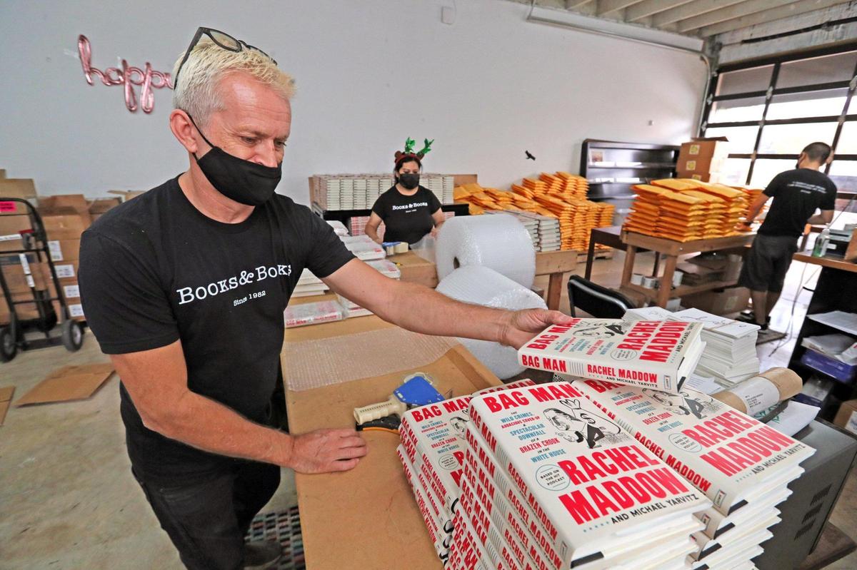 Books & Books employee Gary Cook packs books in bubble wrap as he fulfills holiday orders that are shipping out of the company warehouse on Thursday, December 17, 2020.