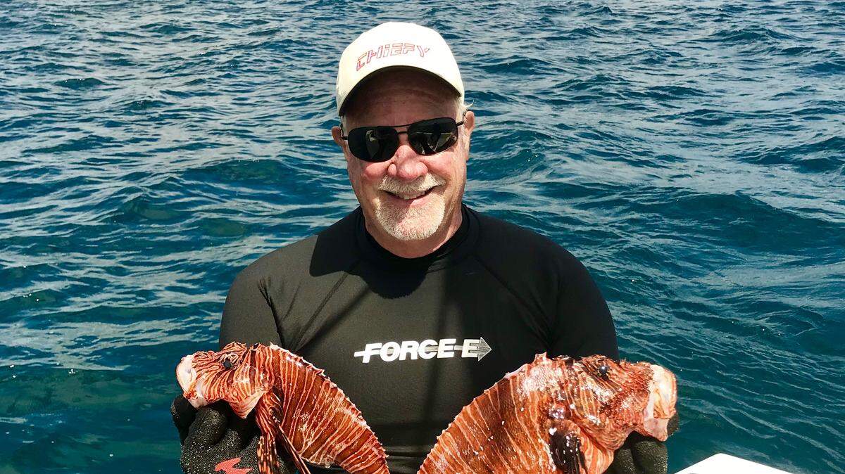 Jim “Chiefy” Mathie of Deerfield Beach holds two nice lionfish that he shot while diving on a local reef.