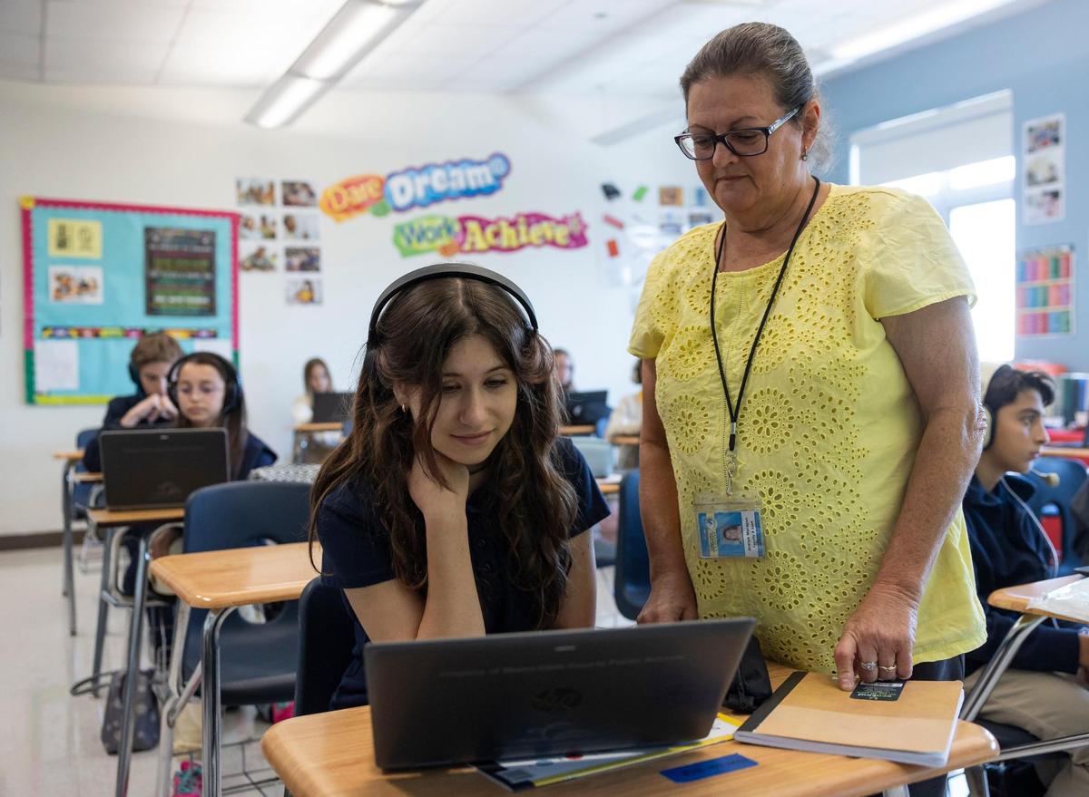 Polina Karpova, 12, a 7th grader from Ukraine, receives assistance from her ESOL teacher, Arelys Morejon, while doing classwork at Aventura Waterways K8 Center.