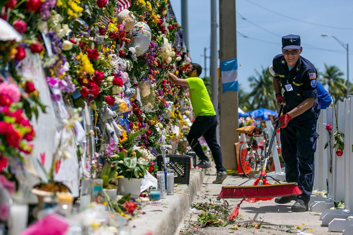 Pastor Abiezer Rodriguez of the Seventh-Day Adventist Church sweeps the ground at the Surfside Wall of Hope & Memorial as rescue teams continue their recovery mission at the collapsed Champlain Towers South condo building in Surfside on Friday, July 9, 2021.