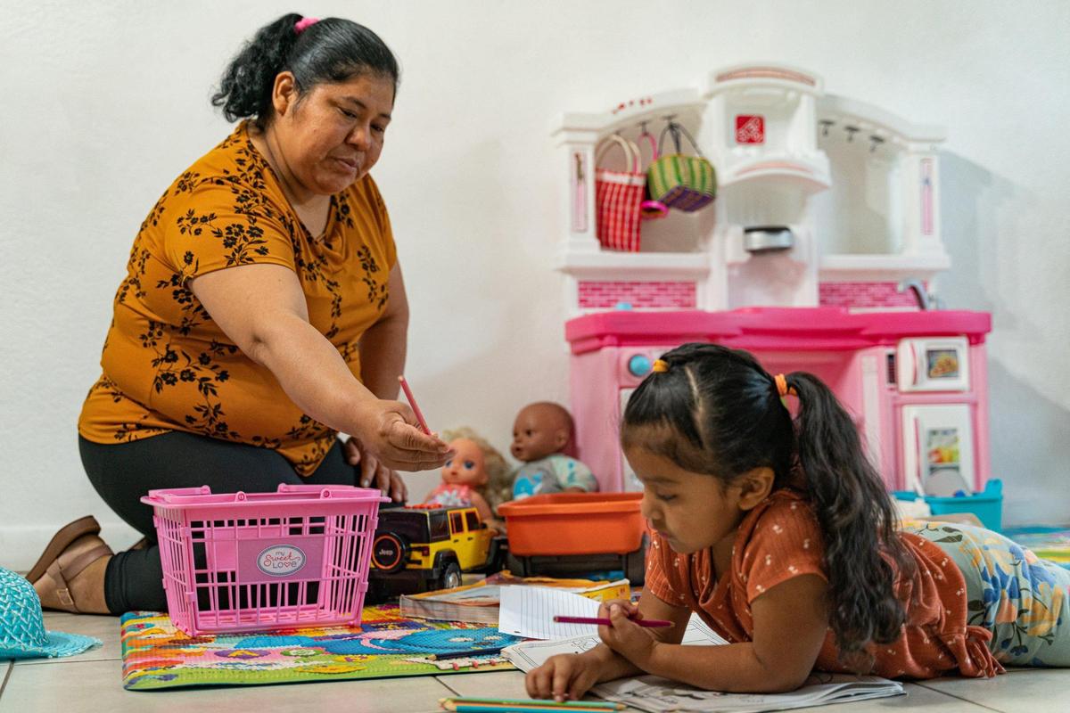 Alida Tomas Mendez hands a colored pencil to her daughter Yaily Mejia in their home in Homestead, Florida on Monday, Nov. 21, 2022.
