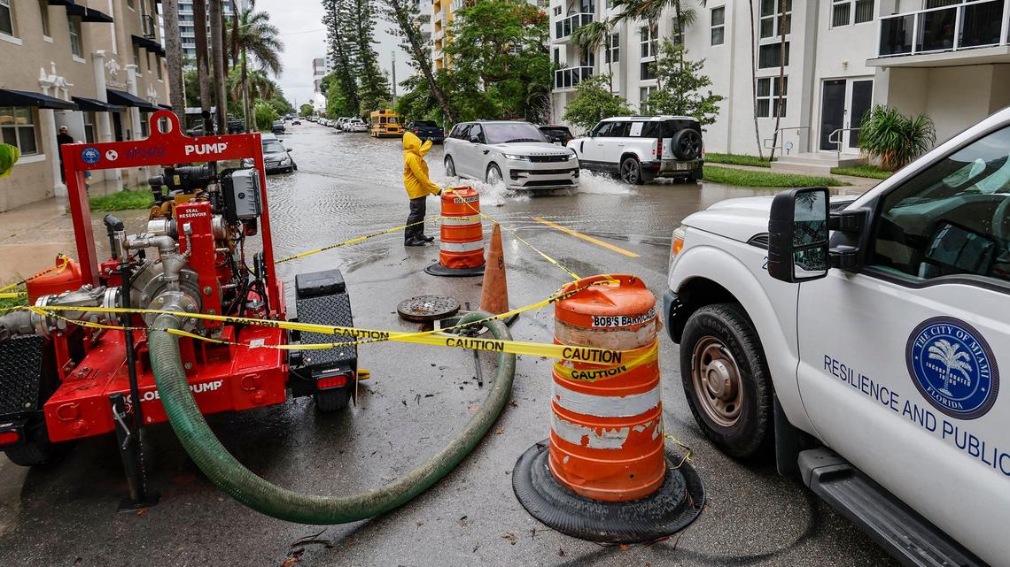 A City of Miami Public Works employee waves towards a vehicle driving through a flooded street in Edgewater along N.E. 23 Street in Miami, Florida on Wednesday, June 12, 2024.