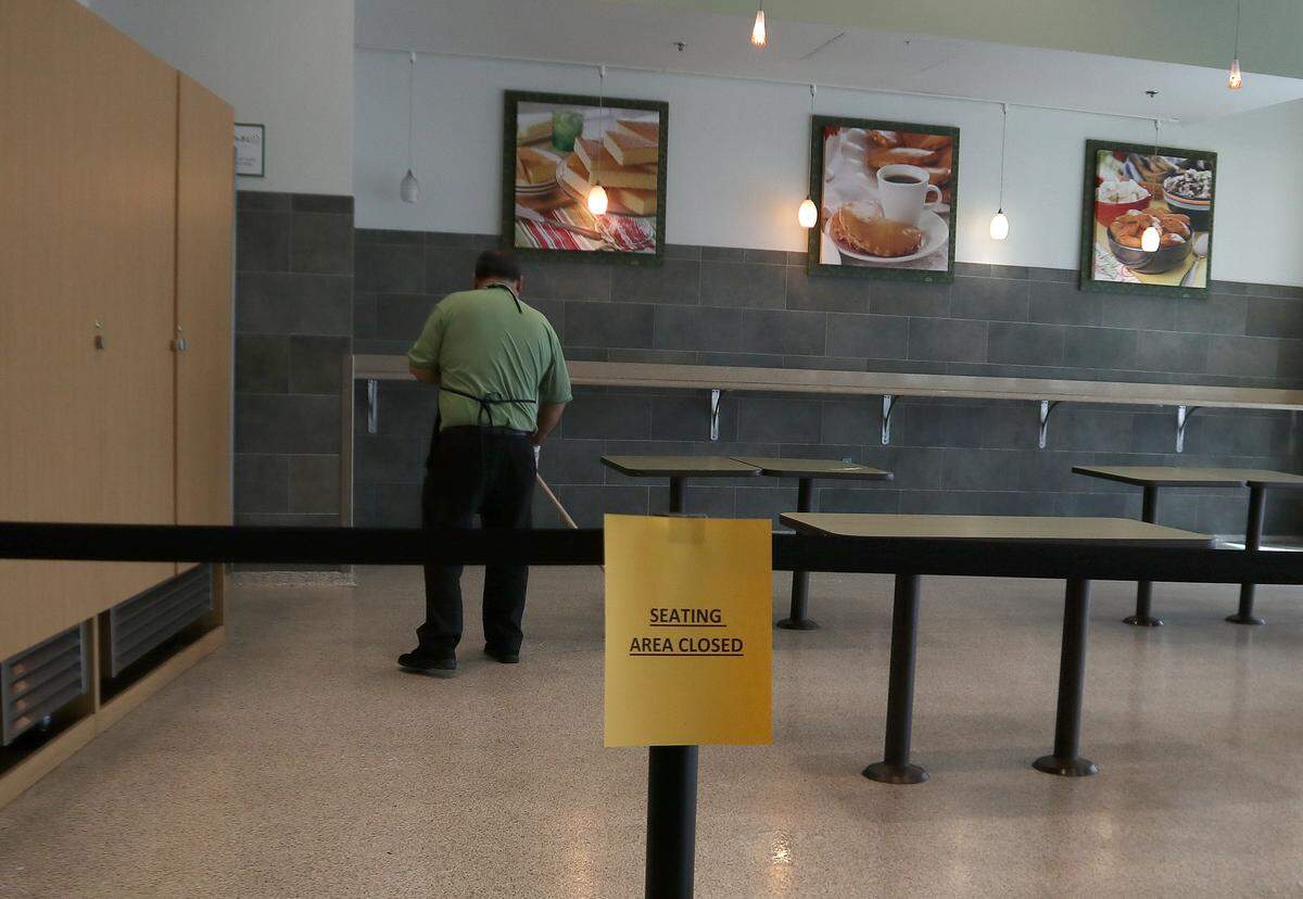 A Publix employee cleans the empty seating area of an in-store Starbucks. The closure of the seating area was part of a countywide closure order in Miami-Dade affecting restaurants, bars and clubs, gyms and entertainment venues that began Wednesday, March 18, 2020.