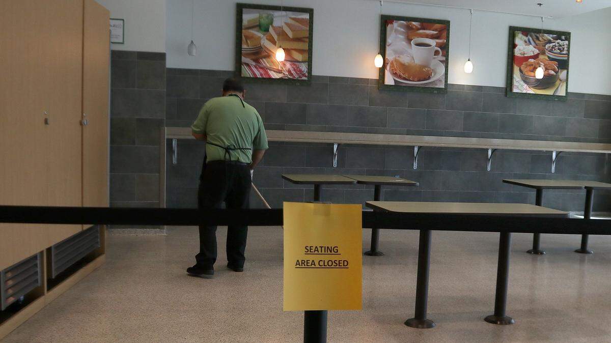 A Publix employee cleans the empty seating area of an in-store Starbucks. The closure of the seating area was part of a countywide closure order in Miami-Dade affecting restaurants, bars and clubs, gyms and entertainment venues that began Wednesday March 18, 2020.