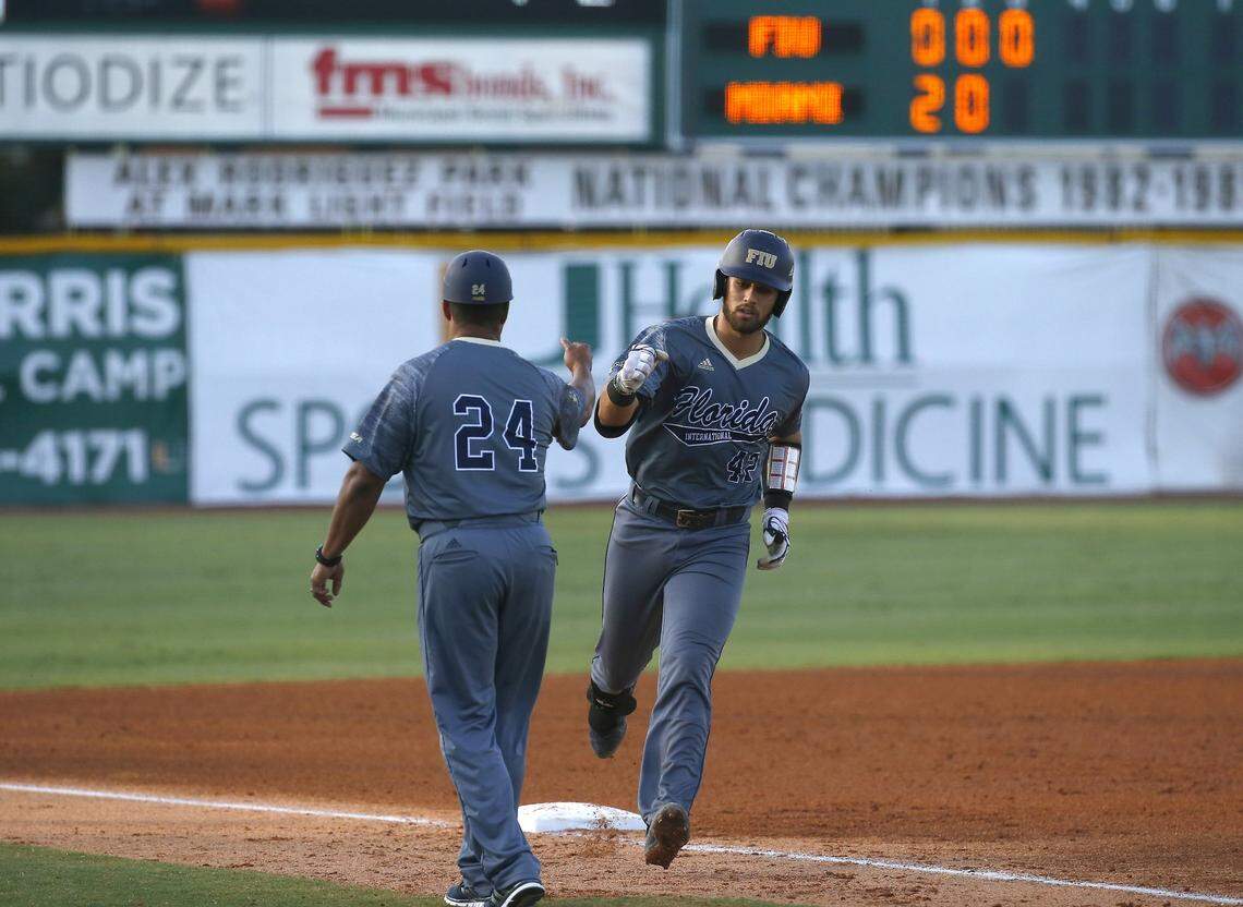 FIU Panthers catcher J.C. Escarra is congratulated by FIU Panthers head coach Mervyl Melendez after hitting a solo home run during the third inning of a NCAA baseball game against the Miami Hurricanes at Alex Rodriguez Park at Mark Light Field on Wednesday, April 26, 2017 in Coral Gables.