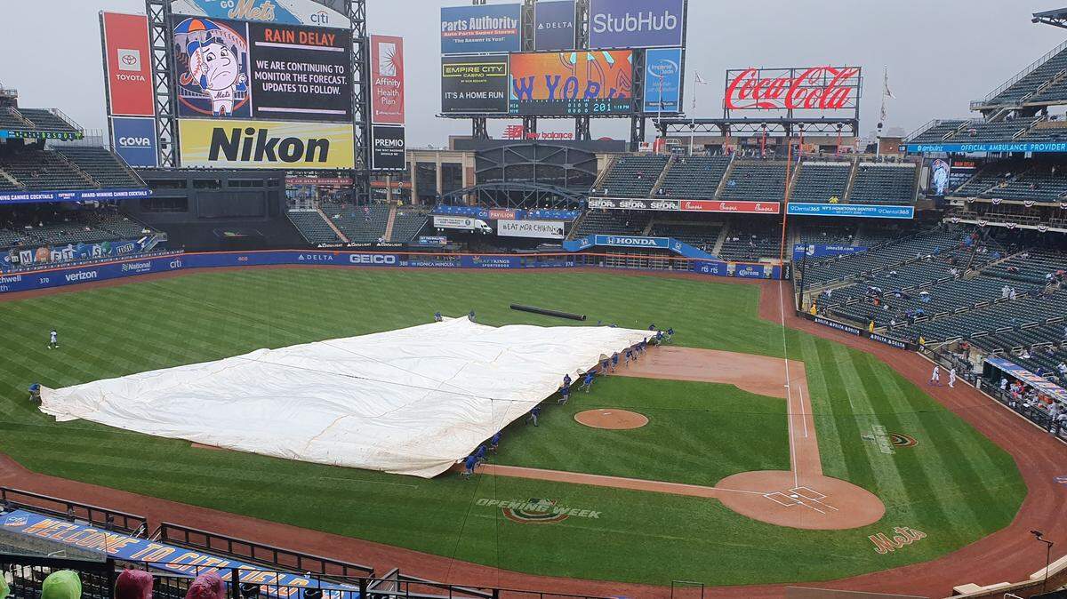 The New York Mets’ groundscrew puts a tarp on the infield at Citi Field during the first inning of a baseball game against the Miami Marlins on Sunday, April 11, 2021.