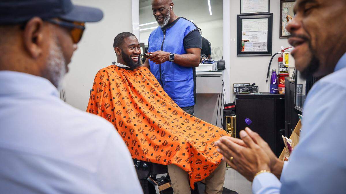Topcuttaz Barbershop owner Mike Stephens, 58, cuts the hair of Jefferson Noel, 31, center, founder of “Barbershop Speaks.” Ruban Roberts, 57, left, and Paul V. Wilson Jr., right, are deep in conversation at Topcuttaz in Miami Gardens. Six Black men - educators, community advocates, activists, and entrepreneurs - gathered at the barbershop to talk about the conditions of Black people in South Florida, a year after the election, and the impact of the first nine months of Trump’s administration.