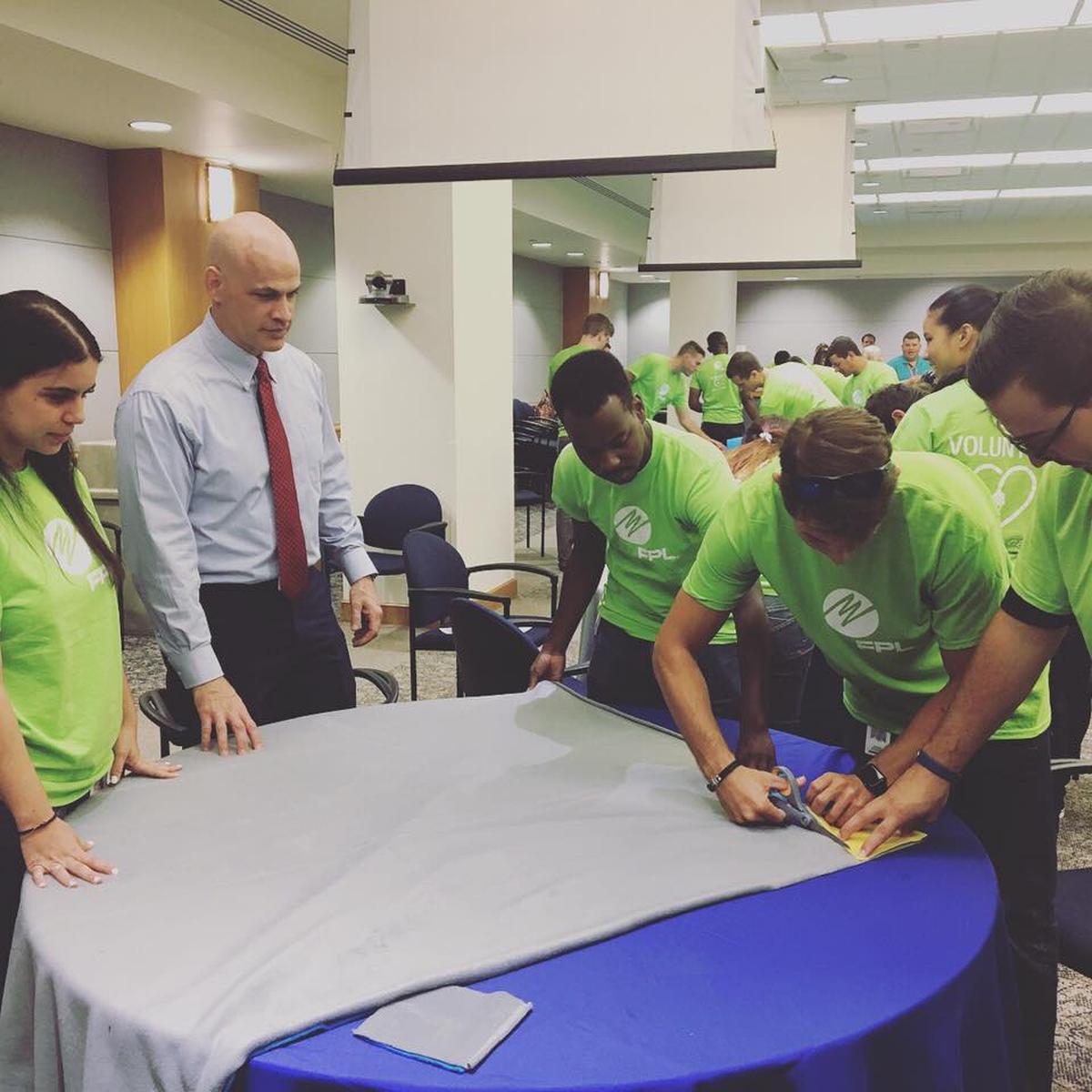 Child Rescue Coalition’s president William Wiltse works with FPL interns as they make care  packages  that contain a blanket and a stuffed bear that police officers can distribute to children in need.