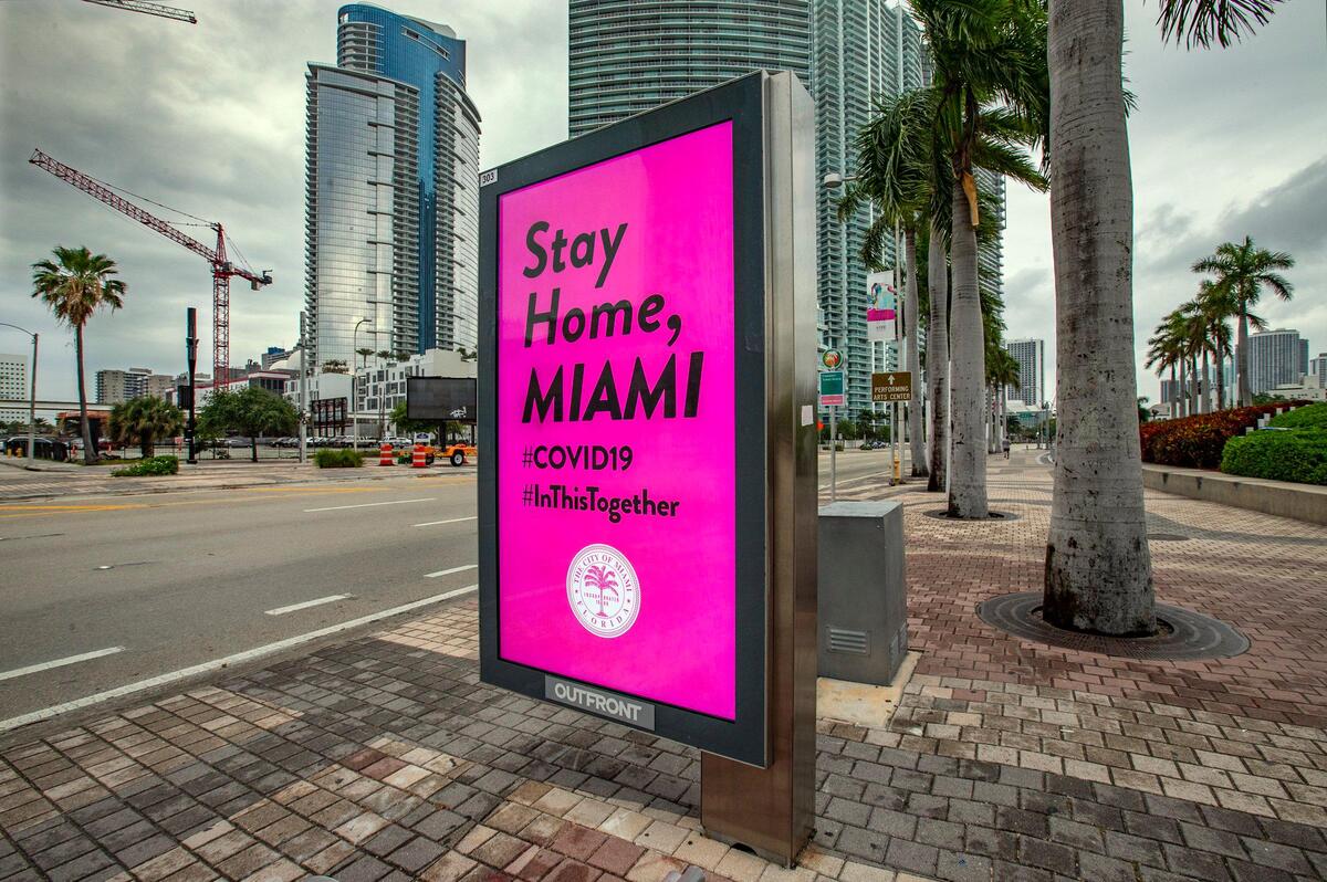 A digital public service announcement is displayed at a bus stop along Biscayne Boulevard in downtown Miami by the City of Miami urging residents to stay home due to the COVID-19 pandemic on Wednesday, April 1, 2020.