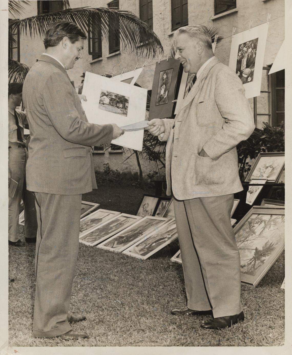 In this Miami Herald file photo from Nov. 19, 1941, a $10 check for the first sale of a clothesline art exhibit staged by Miami artists in the patio of the University of Miami’s administration building is given to instructor Richard Merrick, left, by Bowman Ashe, university president, on behalf of an anonymous buyer.
