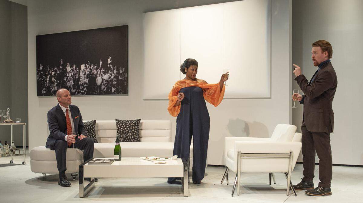 The characters played by Tom Wahl, Rita Cole and Iain Batchelor have a discussion over bubbly in GableStage’s ‘The White Card.’