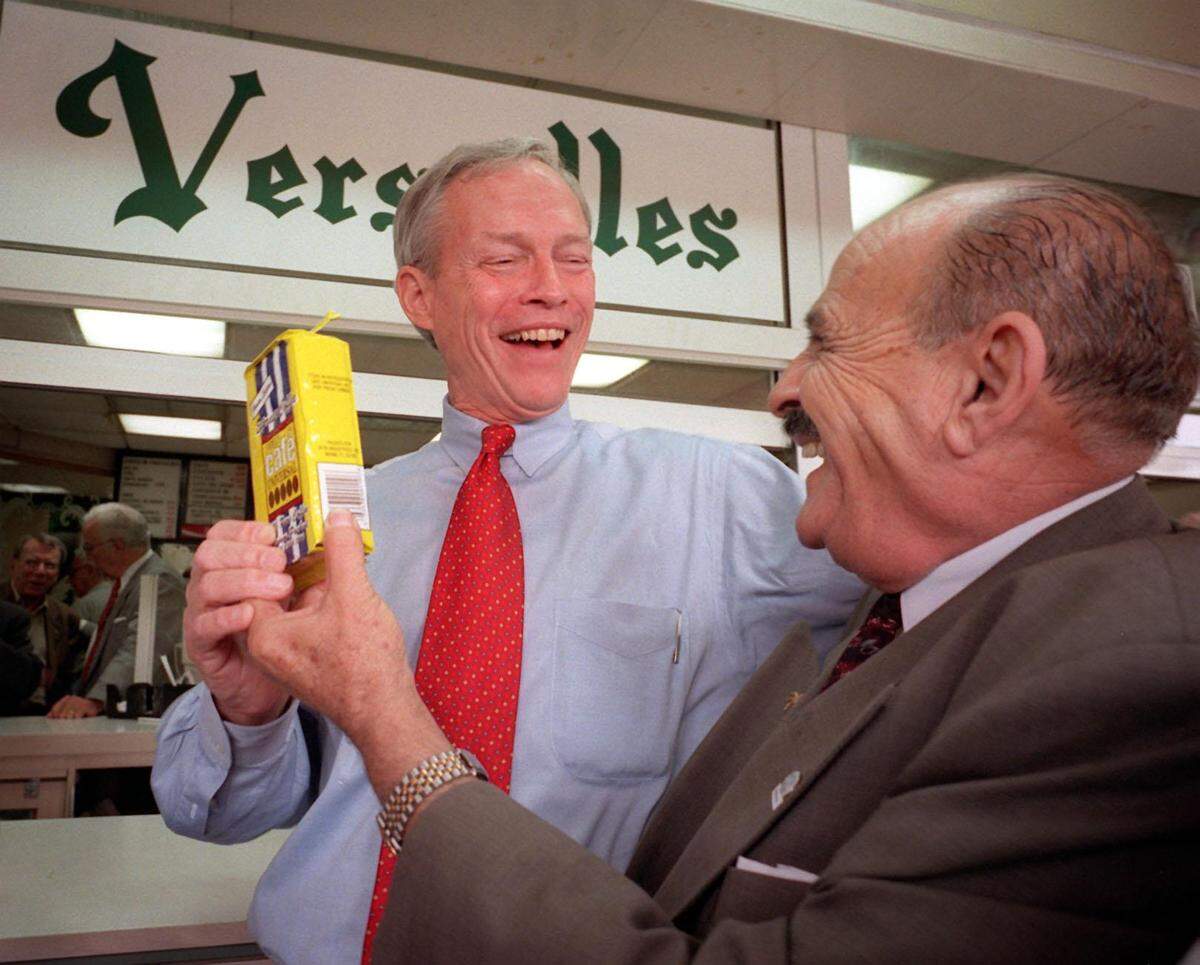 In a photo from February 1998, then-Florida Lt. Gov. Buddy MacKay gets a pack of coffee from CAMACOL president Luis Sabines in front of Versailles restaurant. MacKay was celebrating the victory by Miami cafeterias avoiding expensive new regulations.
