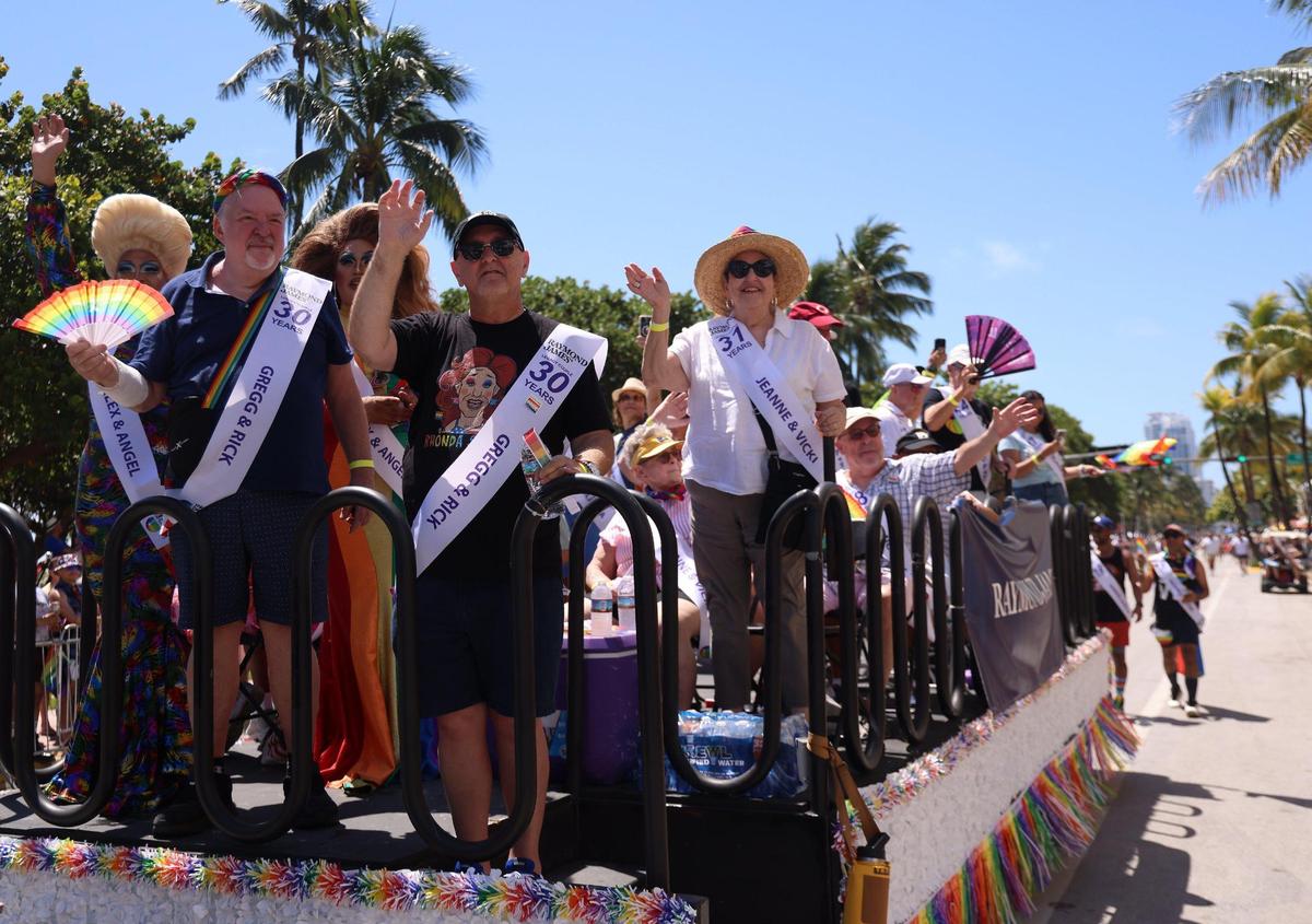 Couples wave to the crowd during the parade up Ocean Drive on Miami Beach, Sunday, April 16, 2023.