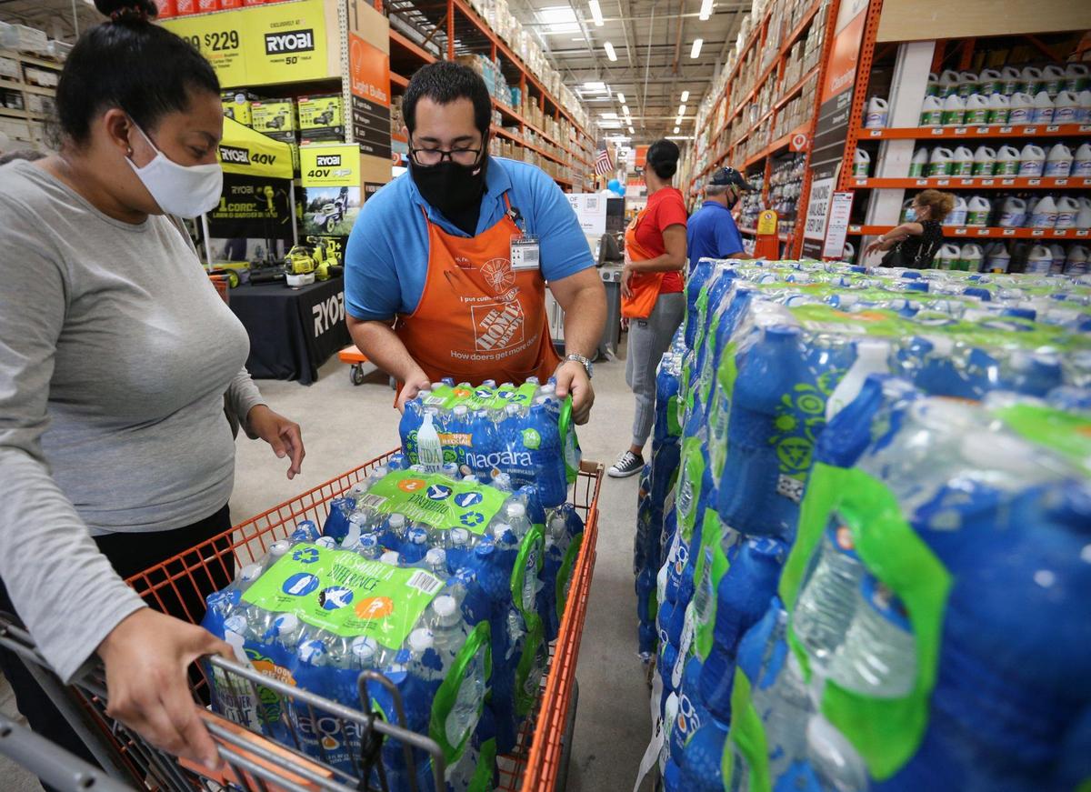 Home Depot department supervisor Arnaldo Gonzalez loads water bottles into Elena Arvalos’ shopping cart as shoppers prepare on Saturday, July 3, 2021, for possible effects of Tropical Storm Elsa in Miami.