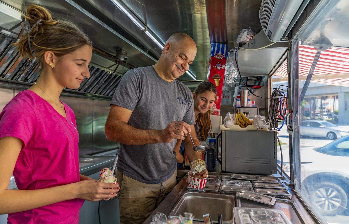 Owner Felipe Grabiel and his daughters Carolina (left) and Natalia Grabiel, serve an order for a customer at their Wall's Old Fashioned Ice cream food truck that has opened on the property of The Big Cheese pizzeria in South Miami, on Tuesday, December 30, 2025.