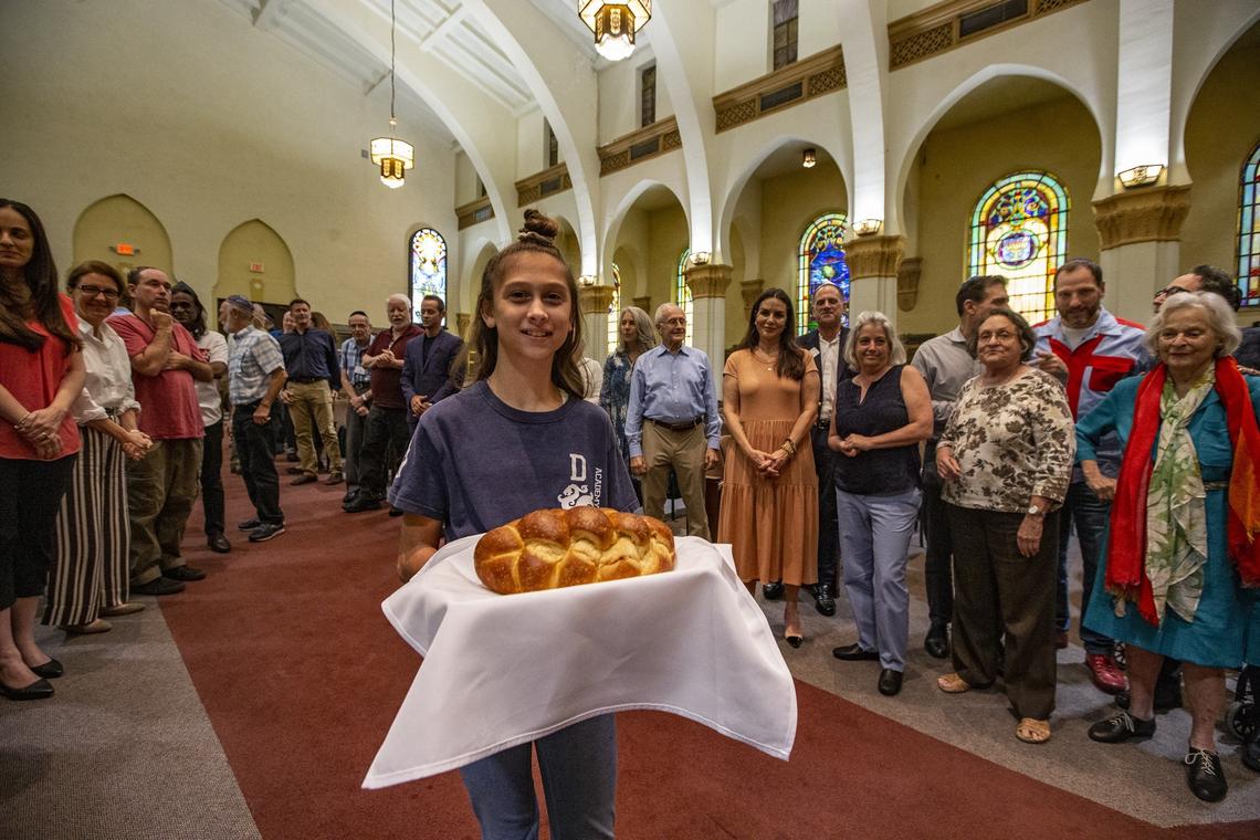 Michaela Sharoni, 9, holds the blessed challah bread during community prayer at Shabbat services on a recent Friday night at Temple Israel of Greater Miami. Rabbi Amy Morrison is the temple’s new senior rabbi.