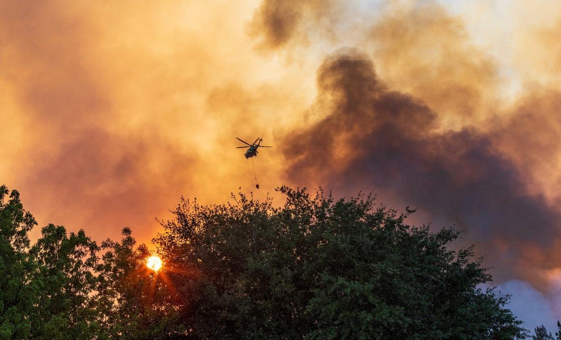 A Miami-Dade Fire fighting helicopter drops water over a fire caused by a grass fire that forced police to shut down SW 8th Street in both directions at SW 137 Avenue due to the heavy smoke in the area, on Sunday, April 14, 2024.