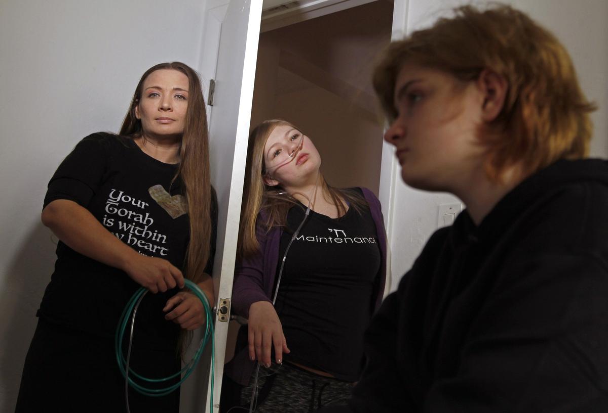 Rebekah Lewis, 17, is connected to an oxygen machine and rarely gets to leave the house because her family can’t afford a motorized scooter or a portable oxygen machine. Left to right: mother Tzedakah Cohen, Rebekah Lewis, 17, center, and Anna Lewis, 13.