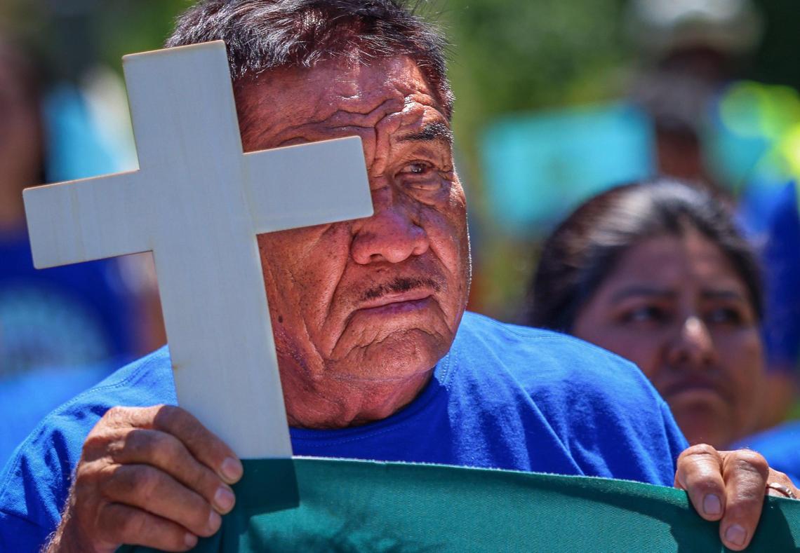 A plant nursery worker holds on to a cross in remembrance of those who lost their lives due to extreme temperatures as about a hundred plant nursery workers and family members march in the Procession for Justice as they came together to honor all the workers who have died too soon because of heat at Sacred Heart Catholic Church in Homestead, Florida on Sunday, April 27, 2025.