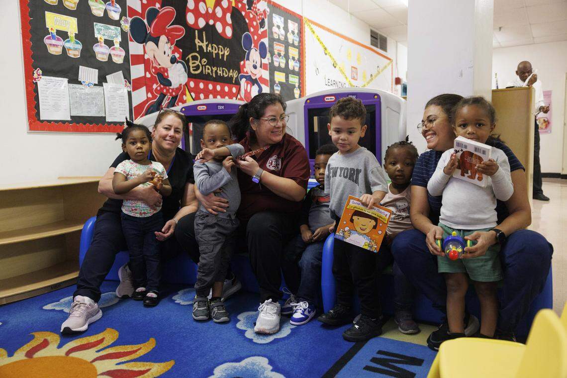 Holding the kids from left to right: Antonieta Acevedo, Juana Roque, and Dineyvis Hernandez, who are going through or have gone through the early childhood education program, sit in the scare that also serves as a practical training room during the day on Tuesday, Oct. 21, 2025, at Lindsey Hopkins Technical College in downtown Miami.