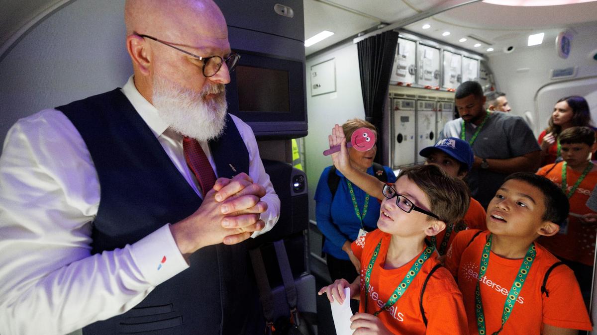 DJ Waddington (izquierda), asistente de vuelo de American Airlines, hablando con Kyler Silva (centro) y Daniel Espinal durante un simulacro de Easterseals South Florida para prepararlos para experimentar los viajes aéreos el martes 23 de julio de 2024 en el Aeropuerto Internacional de Miami (MIA). Muchos de los niños tienen autismo u otras discapacidades que pueden hacer que los aeropuertos sean estresantes, por lo que este recorrido les mostró cómo evitarlo.
