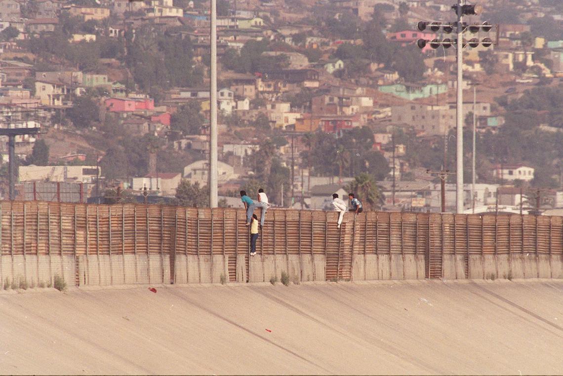 Mexican migrants  leap from the border fence into the United States along the US-Mexico border near Tijuana in this  November 1991 file photo. On Friday Jan. 12, 1996, Attorney General Janet Reno said hundreds of additional law enforcement officers and state-of-the-art equipment would be deployed along the California-Arizona border starting the following week to control an expected surge of immigration from Mexico.