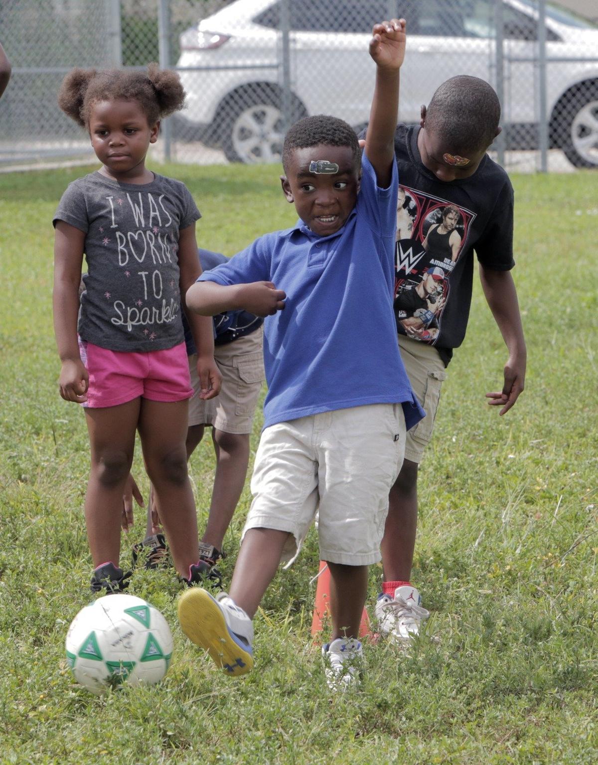 Campers take turns at kicking a soccer ball during a physical activity period at the FIU Summer Academy in Miami on July 24, 2018.