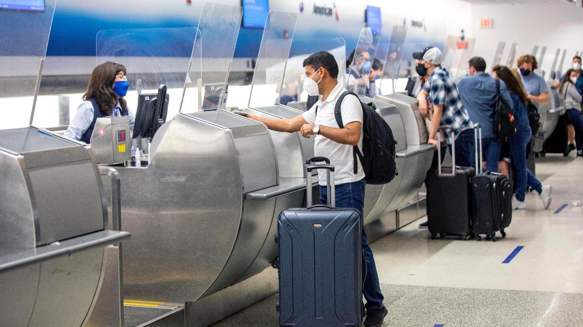 A traveler speaks to an American Airlines employee while checking in at Miami International Airport in Miami, Florida, on Monday, June 7, 2021.
