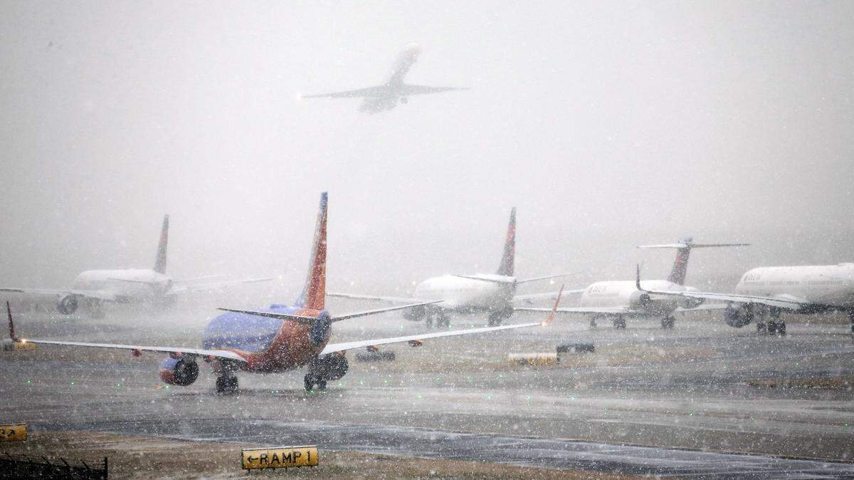 Los aviones se alinean en una pista mientras cae la nieve en el Aeropuerto Internacional Hartsfield-Jackson de Atlanta en diciembre de 2017. Los expertos afirman que volar durante las fiestas de este año será lo más caro en años.