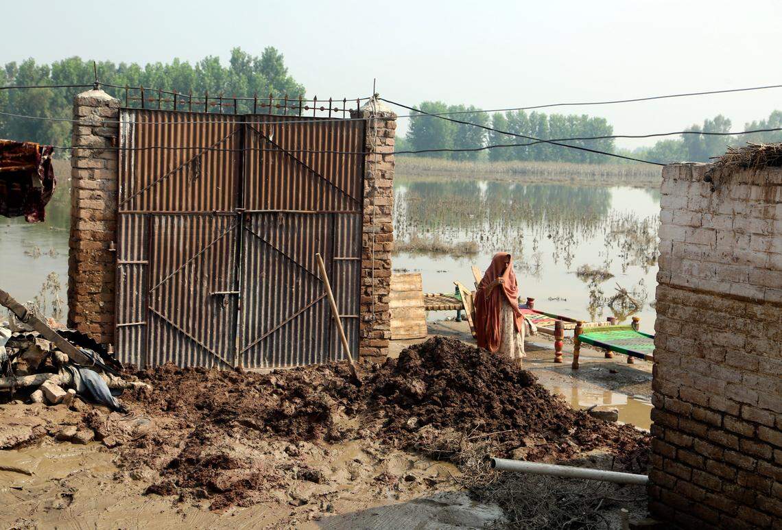 A woman walks near to damage home after heavy rains, in Charsadda, Pakistan, Wednesday, Aug. 31, 2022.