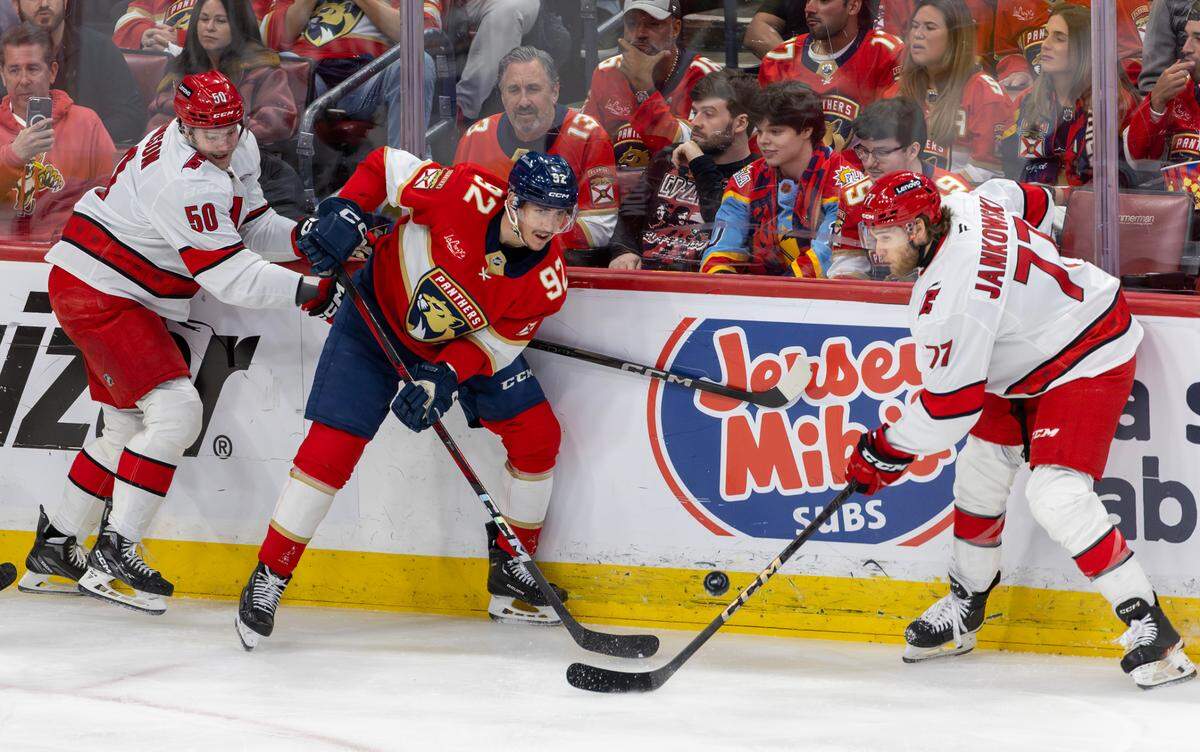 Florida Panthers left wing Tomas Nosek (92) passes the puck under pressure from Carolina Hurricanes left wing Eric Robinson (50) and center Mark Jankowski (77) during the second period of Game 3 in the Eastern Conference Final of the NHL Stanley Cup Playoffs at Amerant Bank Arena on Saturday, May 24, 2025, in Sunrise, Fla.