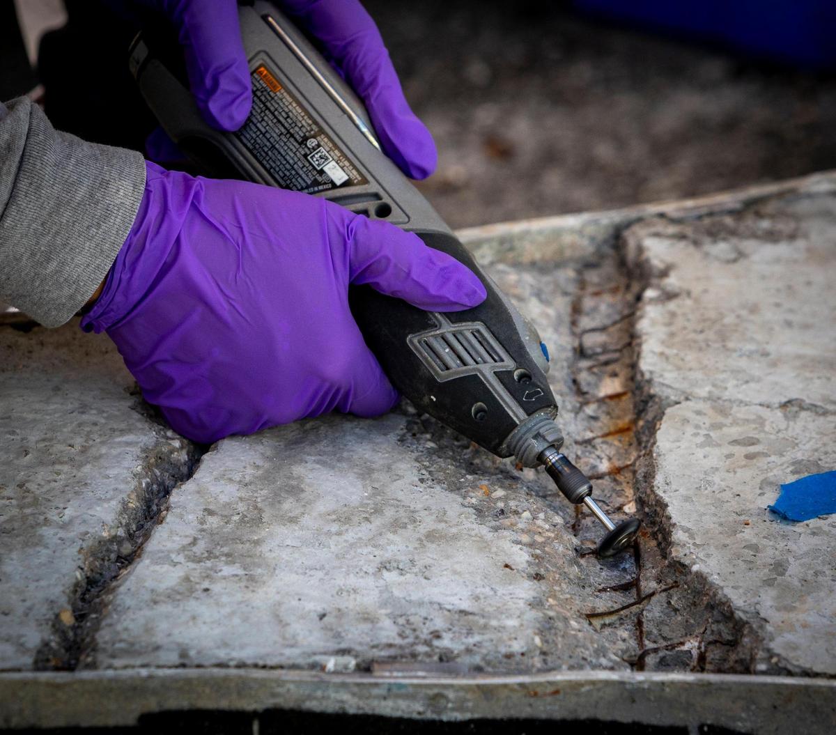 A technician from RLA Conservation carefully digs into the concrete and rusted steel rebar in the back of a section of a 1950s Miami Beach mosaic mural that is undergoing restoration at Wynwood’s Bakehouse Art Complex. The mural, which depicts the Greek god Apollo, was rescued from destruction by preservationists in 2015.