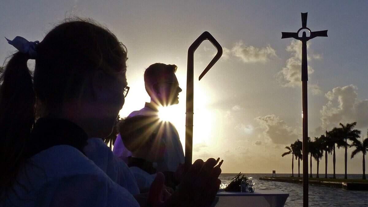 The sun rises behind alter servers during Holy Rosary St. Richard Catholic Church’s Easter Sunrise service at the Charles Deering Estate in Palmetto Bay in 2018.