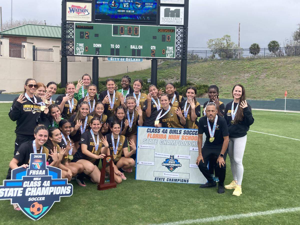 American Heritage girls’ soccer players hold up four fingers to celebrate winning their fourth consecutive state championship after beating Jacksonville Bishop Kenny on Saturday at Spec Martin Stadium in DeLand, Fla.