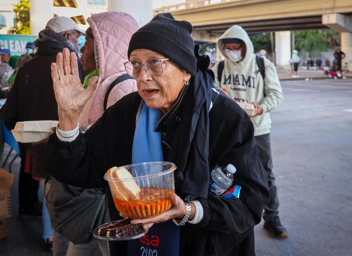 Maria Morales, 75, center, raises her hand while expressing gratitude for a free, warm meal on Thursday, Jan. 9, 2025, in Miami, Florida.