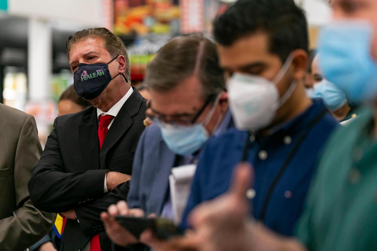 Hialeah Mayor Carlos Hernández listens as Gov. Ron DeSantis speaks during a press conference at a Navarro Discount Pharmacy in Hialeah, Florida, on Tuesday, Feb. 23, 2021. DeSantis announced that dozens of CVS Pharmacy y más and Navarro Discount Pharmacy stores will join the immunization effort.
