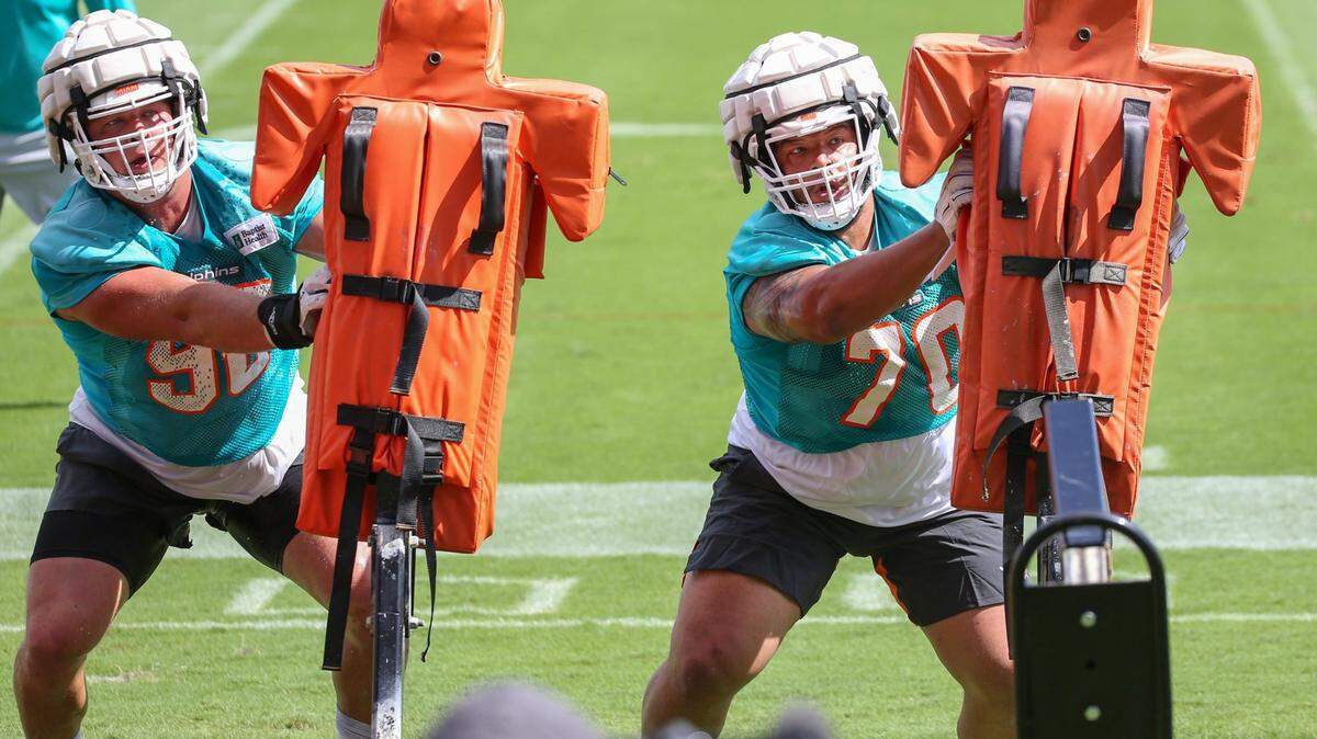 Miami Dolphins defensive lineman Ben Stille (90) and defensive tackle Niles Scott (70) on the practice dummies during drills at Baptist Health Training Complex in Miami Gardens on on Tuesday, August 16, 2022.