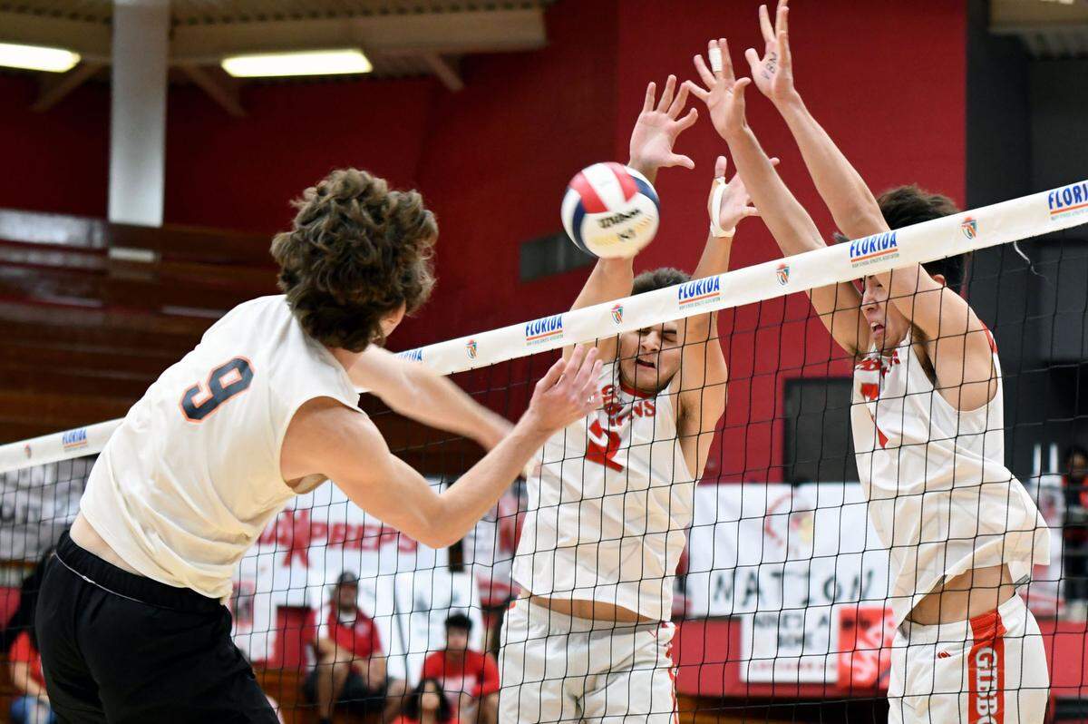 Cardinal Gibbons’ Thiago Zamprogno (left) and Daniel Sappia (right) team up to block a Winter Park shot on Saturday during a semifinal at the FHSAA boys volleyball state championship on Saturday at Polk State College in Winter Haven, Fla.