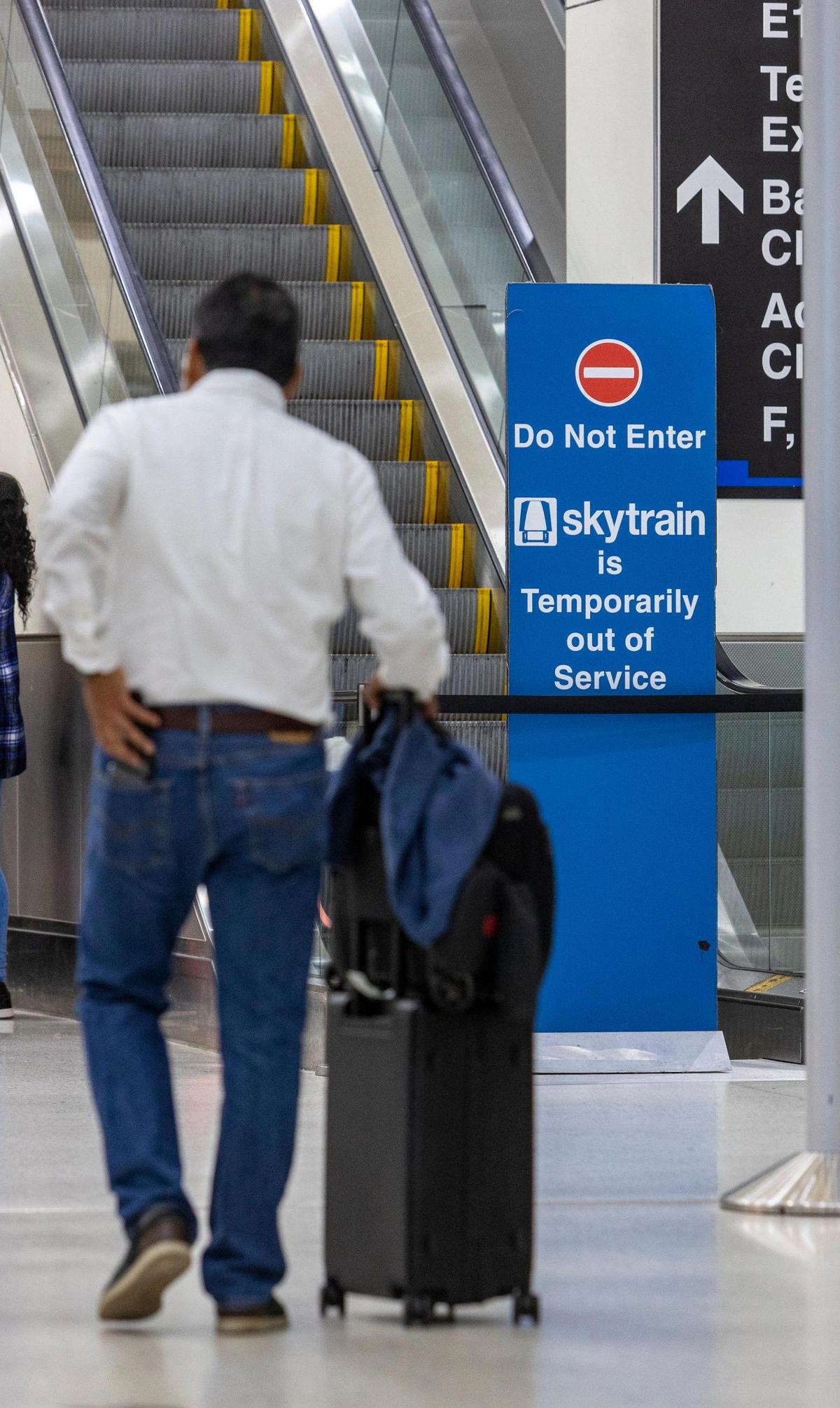 Un hombre con su equipaje pasa por delante de una entrada cerrada al Skytrain en el Pasillo D del Aeropuerto Internacional de Miami. El Skytrain está fuera de servicio indefinidamente y el vehículo de cortesía es la única opción que tienen los pasajeros, además de caminar para ir de un extremo a otro de la terminal, el miércoles 27 de septiembre de 2023.