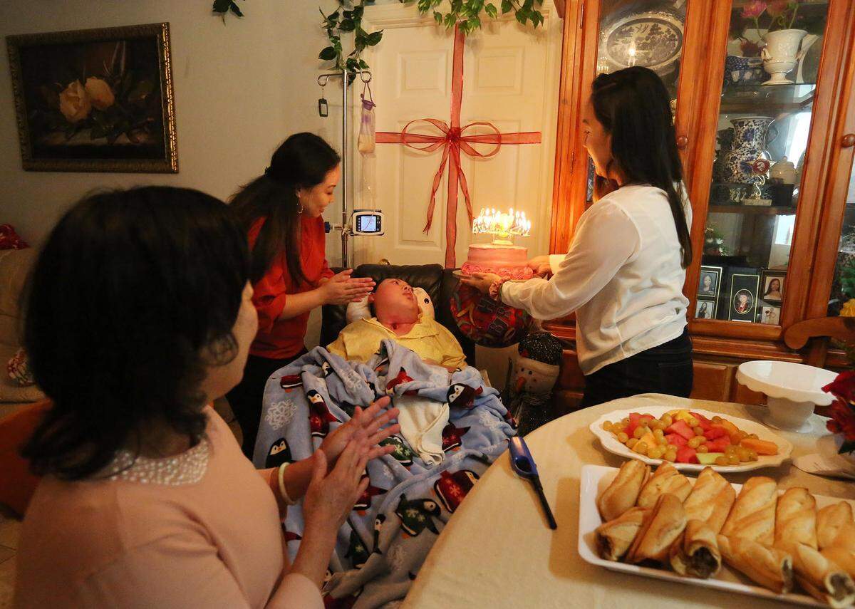 Justin Nguyen, 24, is cared for by his mother, Julie Nguyen, and his sisters, Jessica and Jennifer Pham, in their Jacksonville home. The family was celebrating Julie’s birthday.