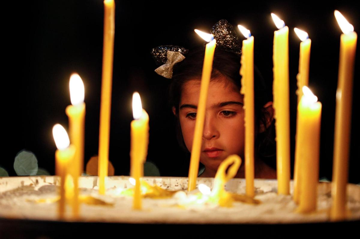Evelina Tavadia-Nesterova, 6, looks at a set of lit candles during a rally and vigil in support of Ukrainians affected by the Russian invasion of Ukraine at St Nicholas Ukrainian Orthodox Church at 5031 SW 100th Ave., in Cooper City, Florida, on March 26, 2022.
