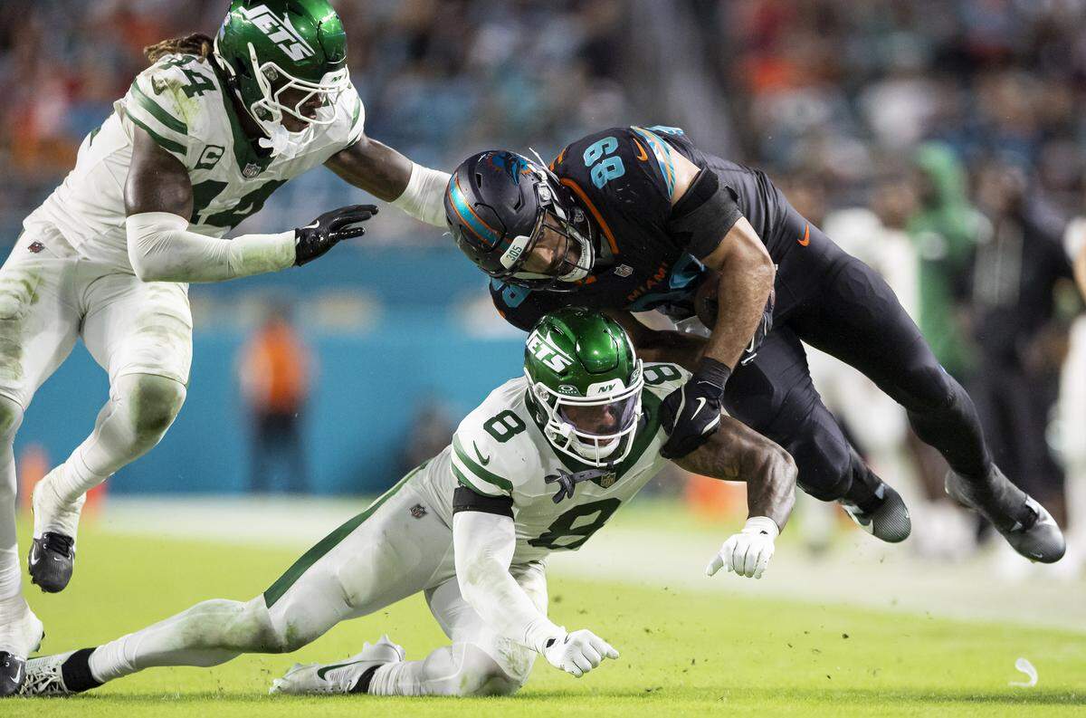 Miami Dolphins tight end Julian Hill (89) is tackled by New York Jets safety Andre Cisco (8) in the second half of their NFL game at Hard Rock Stadium on Monday, Sept. 29, 2025, in Miami Gardens, Fla.