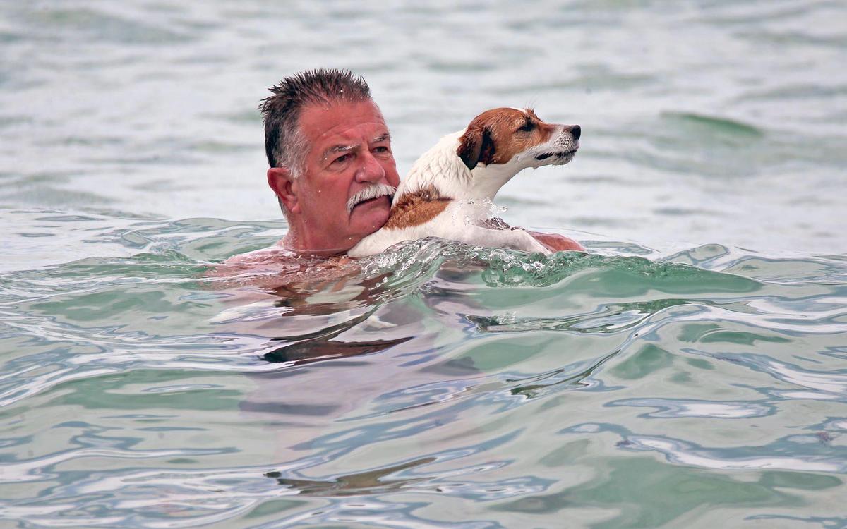 Larry Abascal and his dog, Sweet Pea, cool off in the waters off Haulover Beach in Miami-Dade, Florida, June 21, 2021. Many people trying to find relief from the heat and humidity headed to the beach for the sand and surf.