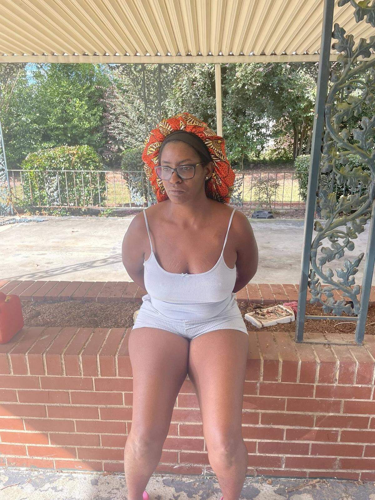 Timishea Price, a Reynolds, Georgia, city council member, sits on a brick wall while handcuffed Wednesday, Oct. 1, 2025, in Reynolds, Ga. Price is accused of helping James Edward Daniels, an escaped Miami-Dade County fugitive, evade capture.