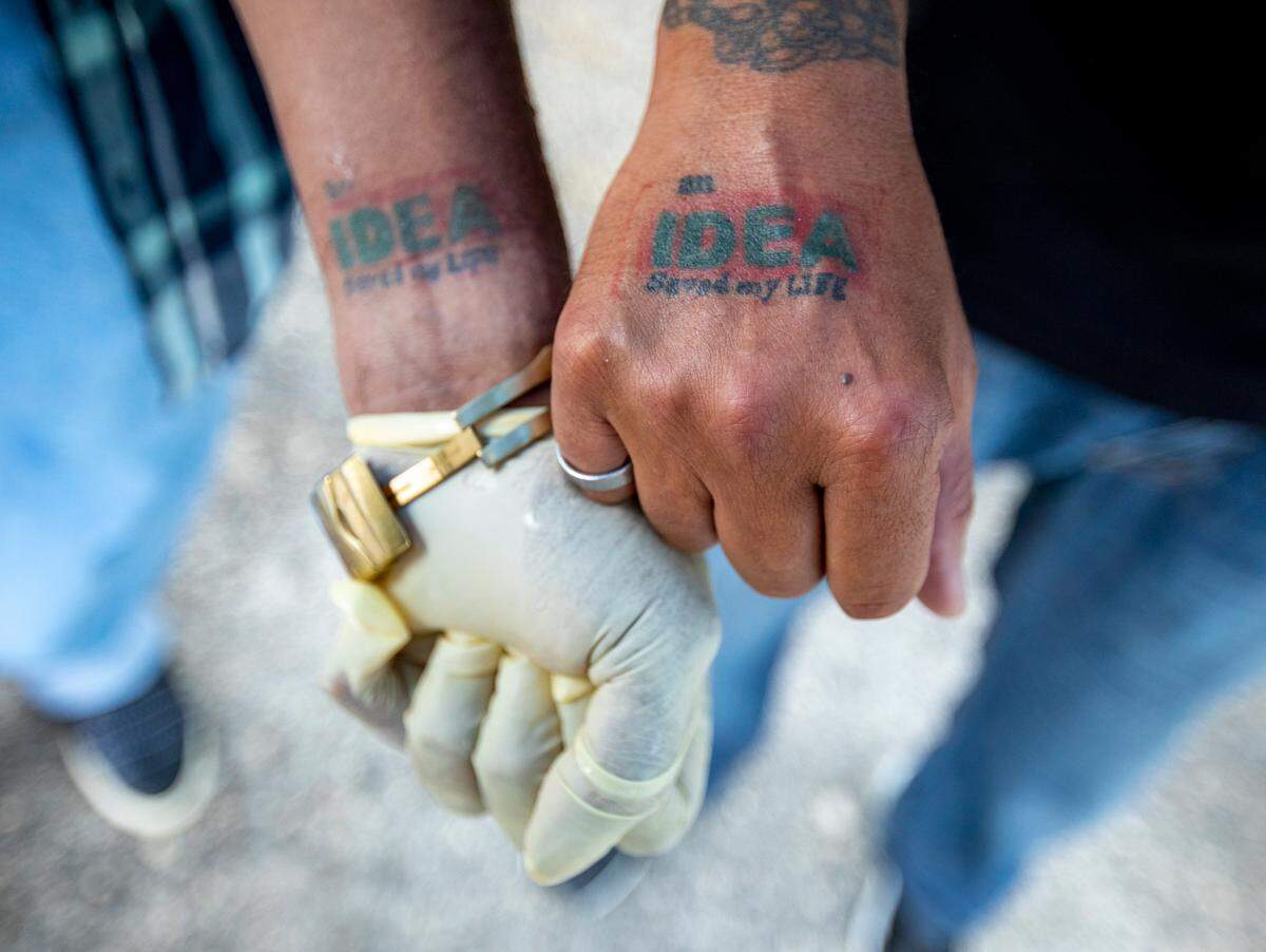 Arrow and Ernesto, friends of the late Margo Lawson, show their set of tattoos, which they got to commemorate the beginning of their sobriety. They say they were helped to achieve sobriety by the IDEA Exchange in Overtown, Florida. Saturday, July 11, 2020.