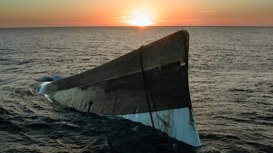 This May 17, 2002, file photo shows the sun setting over the upside-down hull of the Spiegel Grove. The 510-foot-long retired Naval Landing Ship Dock was to be scuttled upright to create an artificial reef off the Florida Keys, but sank prematurely May 17 and rolled over. The vessel fully sank on June 10, 2002.