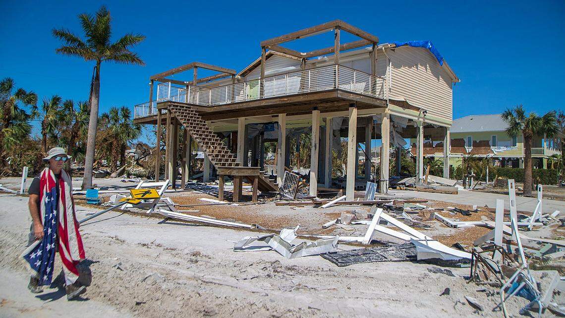 A man carries an American flag as he walks among the destruction along Estero Boulevard in Fort Myers Beach two days after Hurricane Ian hit Florida’s west coast as a Category 4 storm, on Friday September 30, 2022.