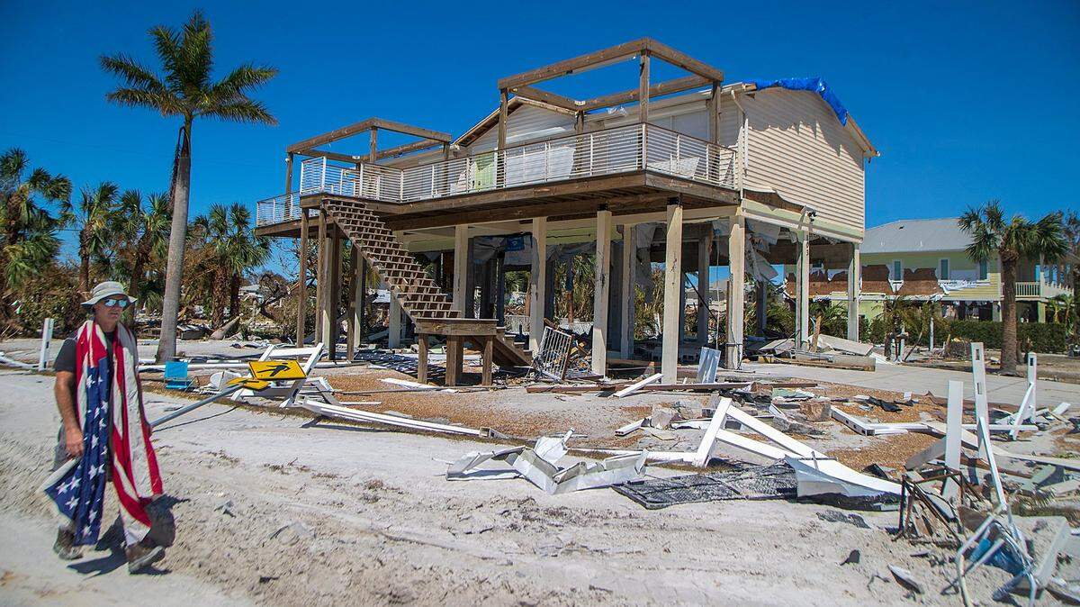 Un hombre llevando una bandera estadounidense mientras camina entre la destrucción a lo largo de Estero Boulevard en Fort Myers Beach, dos días después que el huracán Ian golpeó la costa oeste de la Florida como una tormenta de categoría cuatro el viernes 30 de septiembre de 2022.