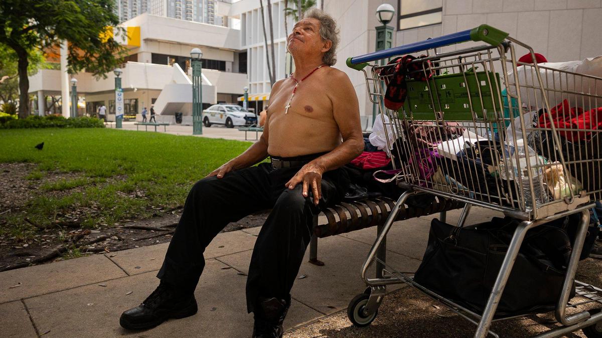 Omar Silas, who has lived on the streets for eight months, relaxes in the shade on Monday, July 17, 2023 at the park across from Government Center in downtown Miami. Silas says he tries to wear white because it keeps him cooler, but he took his shirt off because it was so hot out.